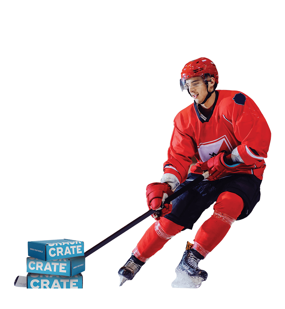 A Canadian hockey player in a red uniform taking a slapshot at a stack of three blue SnackCrates.