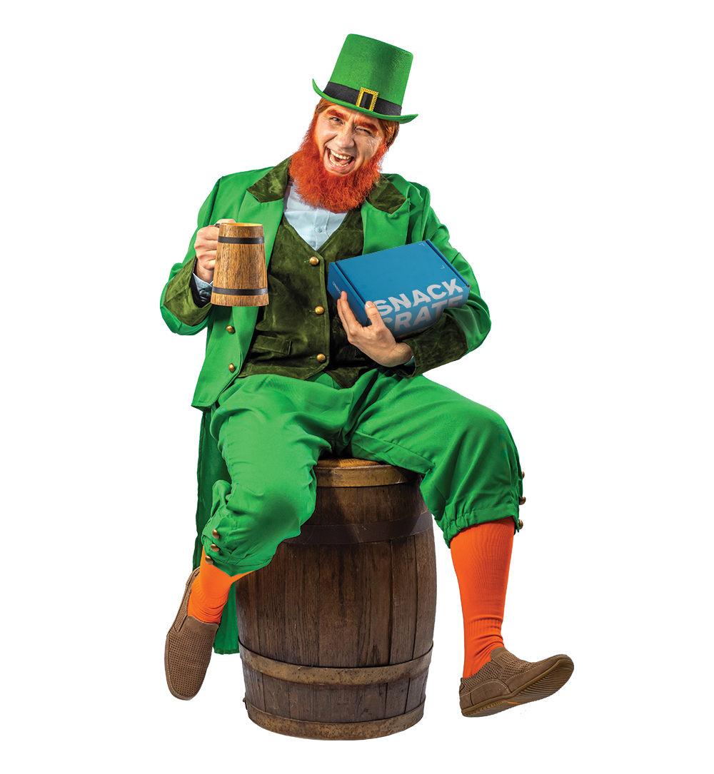 A happy leprechaun sitting on a wooden barrel drinking a pint of ale while holding a blue SnackCrate.
